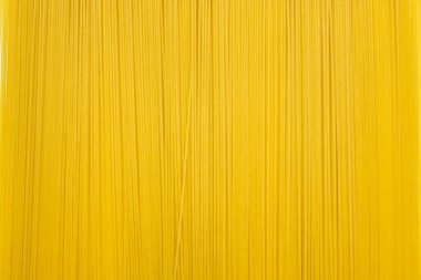 Dikey olarak sıralanmış uzun ve kuru spagetti arkaplanı. İtalyan geleneksel buğday yemeği. Mesaj ve reklam için boş yer var. Uzun, dar bir spagetti pişmeye hazır.