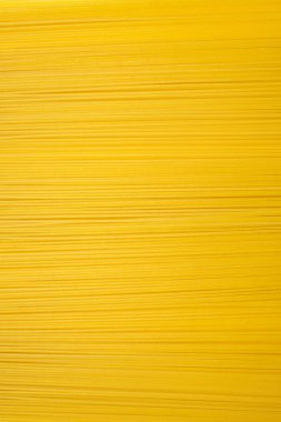 Uzun ve kuru bir spagetti arka planı dikey bir fotoğrafta yatay olarak dizilmiş. Geleneksel İtalyan buğday yemeği. Mesaj ve reklam için boş yer var. Uzun, dar bir spagetti pişmeye hazır.
