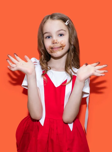 Ένα Κοριτσάκι Κόκκινο Φόρεμα Πασάλειψε Χέρια Και Πρόσωπό Της Σοκολάτα — Φωτογραφία Αρχείου