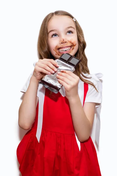 Счастливая Маленькая Девочка Красном Платье Съедает Плитку Шоколада Белом Вертикальном — стоковое фото
