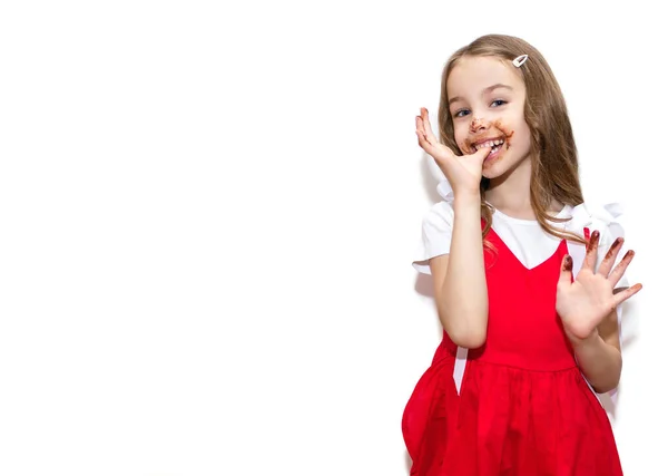 Little Girl Red Dress Eats Chocolate Licks Her Fingers Standing — Stock Photo, Image