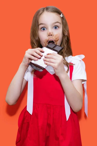 Uma Menina Vestido Vermelho Segura Uma Barra Chocolate Suas Mãos — Fotografia de Stock