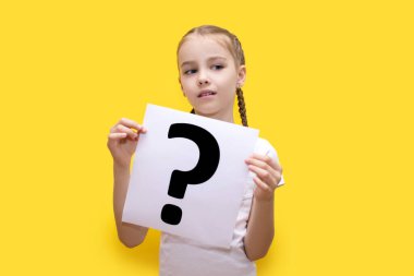Sarı arka planda soru işareti olan bir sayfa kağıt tutan kız. Merak ya da kendinden şüphe etme kavramı. Bir çocuğun elindeki beyaz kağıttaki soru işareti. Kız düşündü ki...