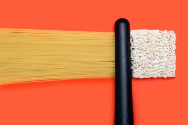Spagetti bigudileri ve turuncu arka planda dalgalı hazır şehriyeler. Saç düzleştirme ya da kıvırma kavramı. Saç bakımı ve yemek tanıtımı