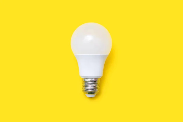 An energy-saving light bulb on a yellow background in the center of the image. Saving energy and finances. Electrical equipment and the evolution of light. disposable light bulb