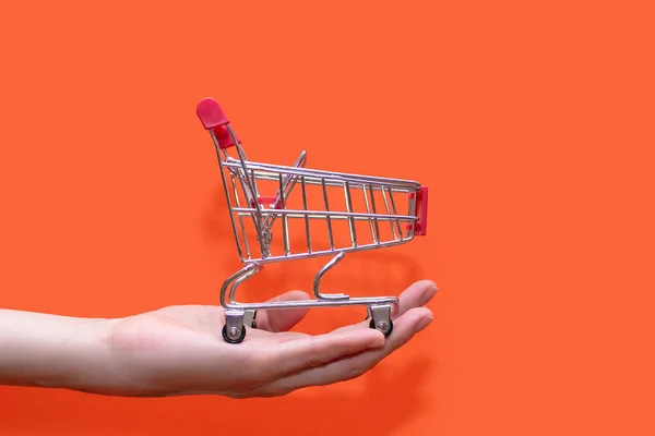 Mały Wózek Sklepowy Ręku Pomarańczowym Tle Zbliżenie Koncepcja Kupna Sprzedaży — Zdjęcie stockowe