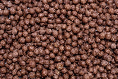 Background of round chocolate flakes in the form of balls. The concept of fast carbohydrate breakfast. Free space for text and advertising. American style chocolate balls background