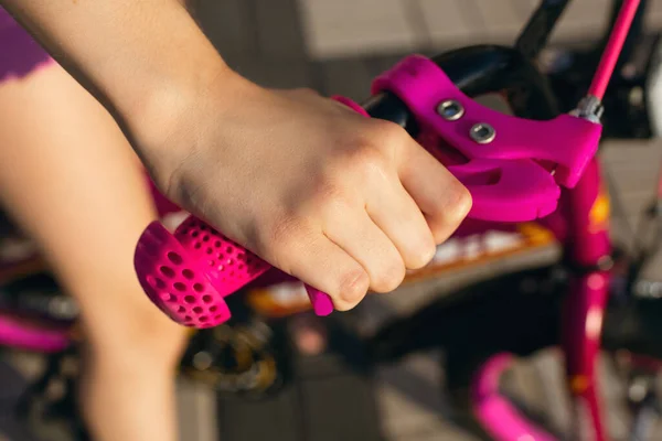 Handbrake on a pink children\'s bike. The hand of the child pressed the handbrake. Bike safety concept. How to teach your child to ride a bike safely and use the brakes