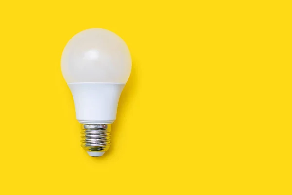 Energy saving light bulb on a yellow background with free space for text. Energy and financial savings. Electrical equipment and the evolution of light. Free space for text