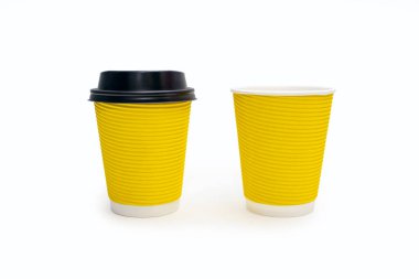 Two disposable yellow cardboard coffee cups on a white background. One coffee cup with plastic lid and one without. A variety of ways to drink coffee or tea from disposable cups