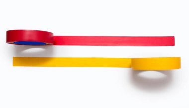 Yellow and red electrical tape glued to a white background. Red and yellow sticky tapes for insulating electricity and wires. Tool for an electrician in working with electrical wiring