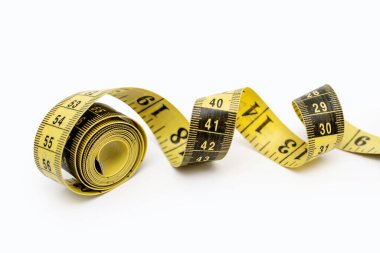 Yellow measuring tape twisted on a white background. Tool for measuring length and volume. Yellow and black twisted tape for measuring in the sewing industry and the human body