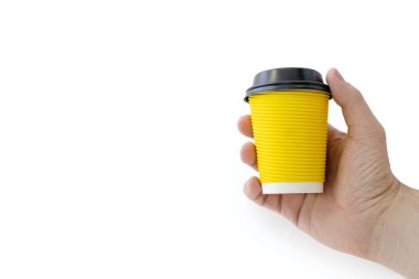 Yellow cardboard cup for coffee in hand on a white background. A man holds a disposable cardboard cup with coffee and a plastic lid. Convenient container for drinking drinks. Free space for text