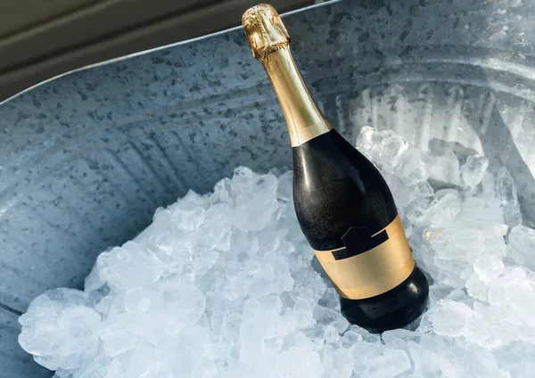 A bottle of champagne in a metal container filled with ice. Chilled alcohol in the form of champagne with ice at a party. Free space for text