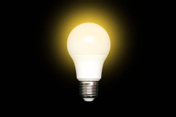 Glowing energy-saving light bulb on a black background in the center of the image. Saving energy and finances. Electrical equipment and the evolution of light