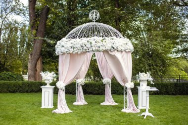 Beyaz çiçeklerle süslenmiş yeşil bir çimenlikte güzel bir düğün kemeri. Yeni evlilerin nikâh törenine hazırlanıyorum. Düğün kemeri, çadır şeklinde törenler için.