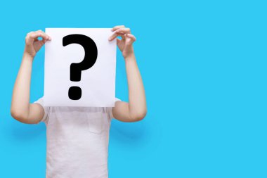 Çocuk mavi arka planda soru işareti olan bir kağıt parçası tutuyor ve yüzünü örtüyor. Merak ya da kararsızlık kavramı. Metin için boş alanı olan beyaz kağıt üzerindeki soru işareti