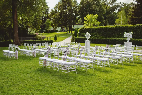 婚礼用的绿色草坪上的白色椅子在等客人 用鲜花和织物装饰的椅子形式的漂亮的座位区域 为婚礼做准备 — 图库照片