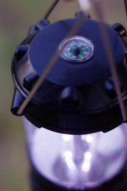 Bir kadın elinde bir lamba tutuyordu. Lambanın üzerinde pusula var. Kamp LED lambası.