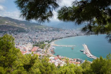 Türkiye 'de deniz, ağaçların arasından Alanya. Arka planda deniz feneri var. Yukarıdan görüntüle