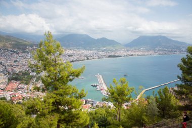 Türkiye 'de deniz, ağaçların arasından Alanya. Arka planda deniz feneri var. Yukarıdan görüntüle