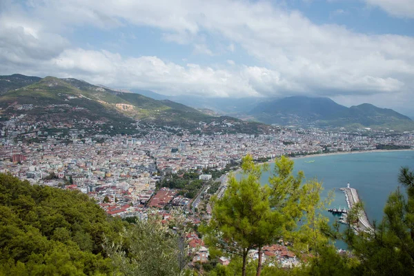 Türkiye 'de deniz, ağaçların arasından Alanya. Arka planda deniz feneri var. Yukarıdan görüntüle.