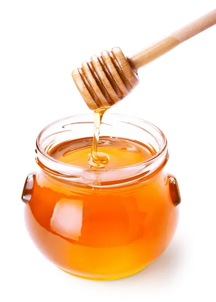 Glass jar of honey with wooden drizzler isolated on white — Stock Photo, Image