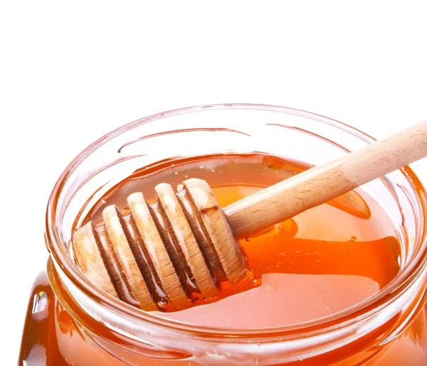 Glass jar of honey with wooden drizzler on white — Stock Photo, Image