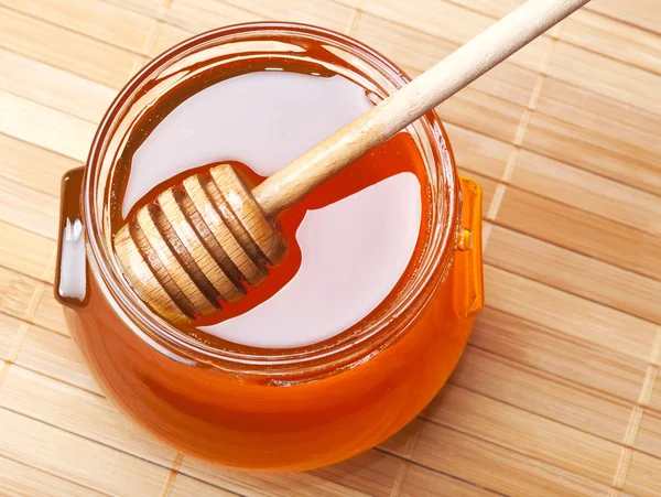 Tarro de vidrio de miel con rociador de madera — Foto de Stock