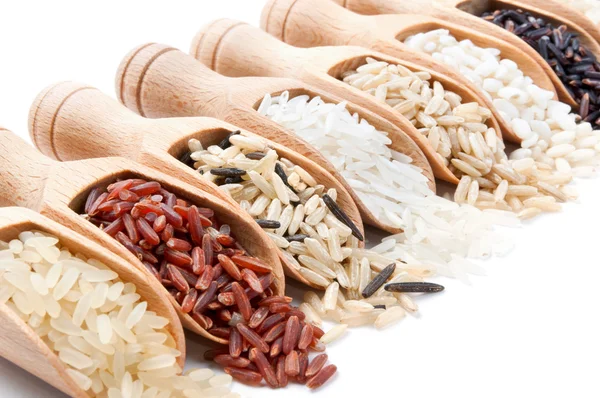 Wooden scoops with different rice types scattered from them — Stock Photo, Image