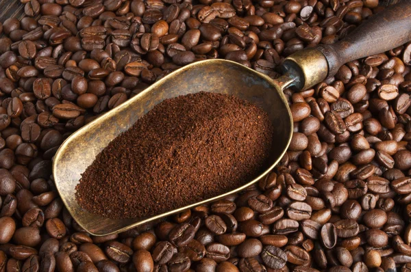 Vintage scoop with ground coffee on coffee beans — Stock Photo, Image