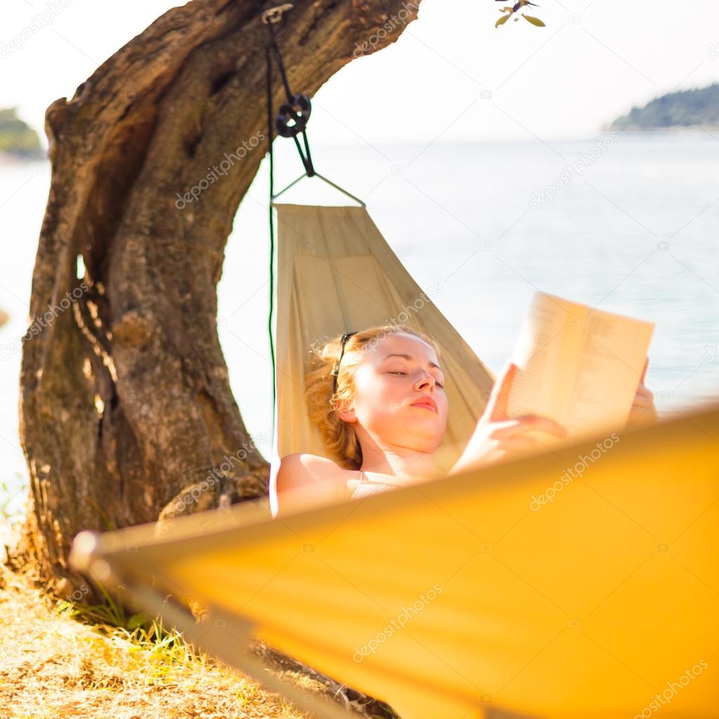 Lady reading book in hammock.