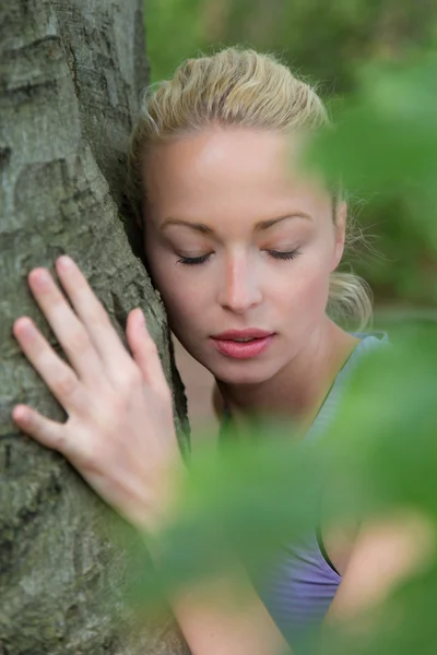 Jonge vrouw knuffelen een boom. — Stockfoto