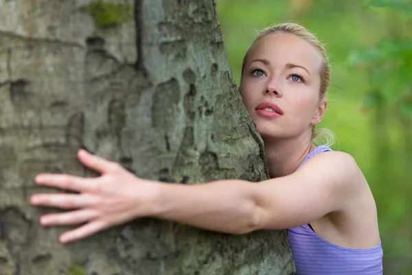 Ung kvinna kramar ett träd. — Stockfoto