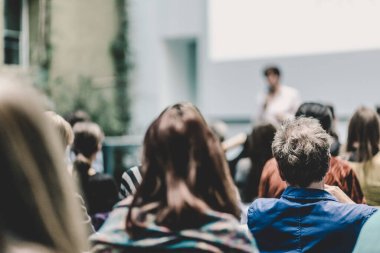 Üniversitedeki konferans salonunda sunum yapan kadın..