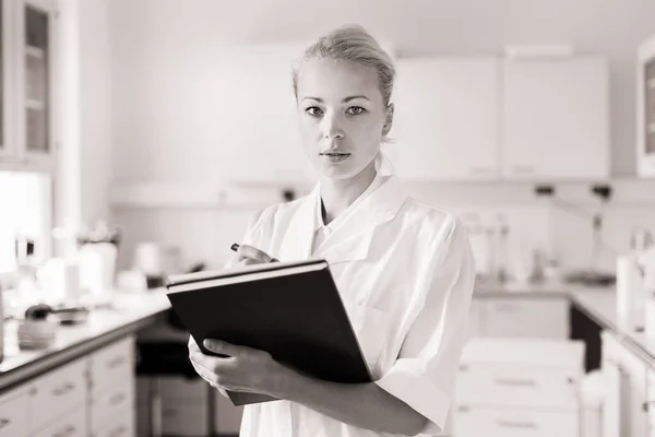 Portrait of young, confident female health care professional taking notes during inventory in scientific laboratory or medical doctors office — Stock Photo, Image