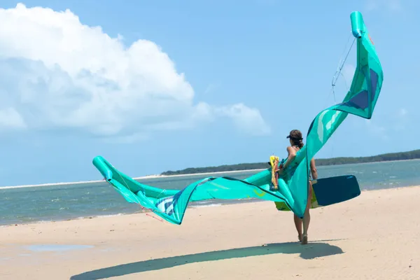 Sexy chica kitesurf caminando en playa de arena sosteniendo cometa y kiteboard. — Foto de Stock