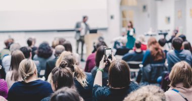 Üniversitedeki konferans salonunda sunum yapan adam.