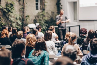 Üniversitedeki konferans salonunda sunum yapan adam.