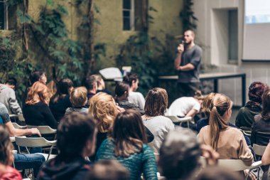 Üniversitedeki konferans salonunda sunum yapan adam.