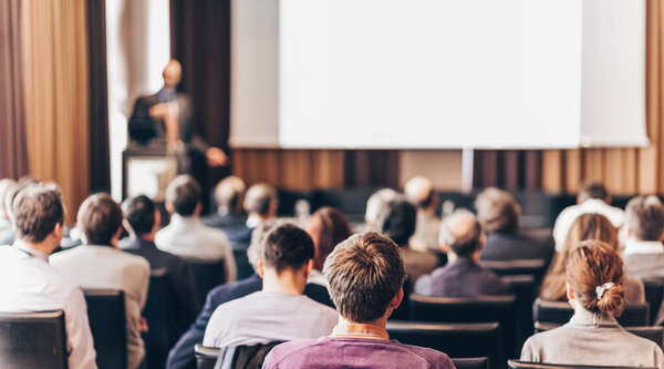Докладчик выступает на деловой встрече. Зрители в конференц-зале. Бизнес и предпринимательство