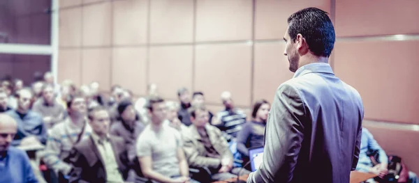 Mluvčí má přednášku na firemní obchodní konferenci. V konferenčním sále nepoznatelní lidé. Obchodní a podnikatelská akce — Stock fotografie