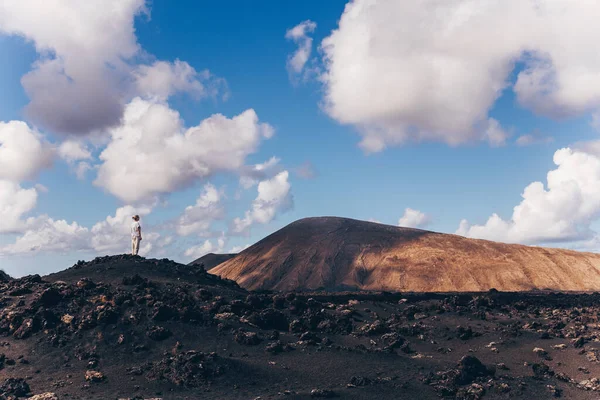 Woman rising hands up in the sky, enjoying amazing views of volcanic landscape in Timanfaya national park on Lanzarote, Spain. Freedom and travel adventure concept. — Stock Photo, Image