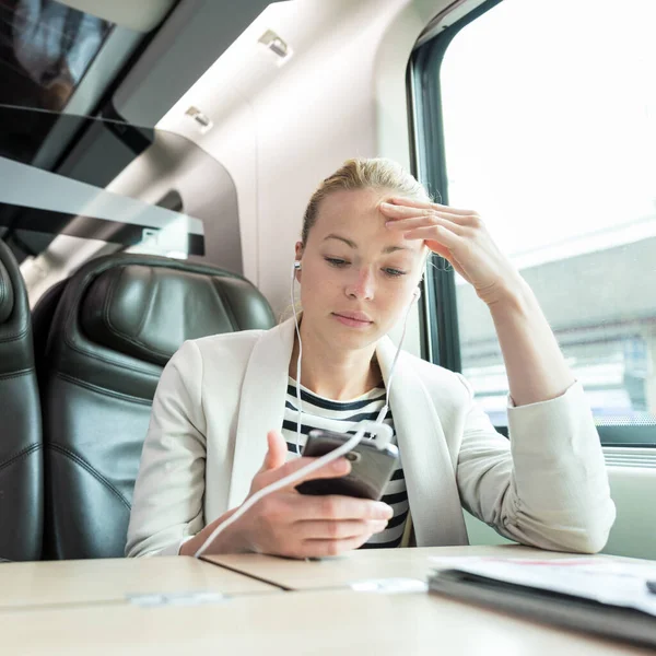 Bizneswoman komunikujących się przez telefon komórkowy podczas podróży pociągiem. — Zdjęcie stockowe