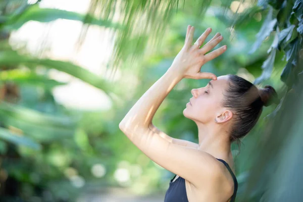 Female meditating and practicing yoga in tropical rainforest. Beautiful young woman practicing yoga outdoor with tropical forest in background. — Stock Photo, Image