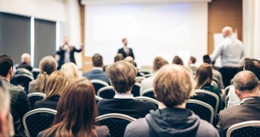 Benim bir sorum var. Bir grup iş adamı konferans salonunda oturuyor. İş adamı kolunu kaldırıyor. Konferans ve Sunum. İş ve Girişimcilik