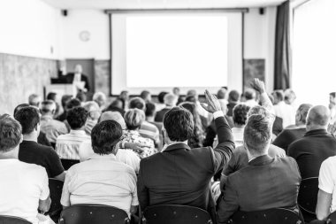 Benim bir sorum var. Bir grup iş adamı konferans salonunda oturuyor. İş adamı kolunu kaldırıyor. Konferans ve Sunum. İş ve Girişimcilik