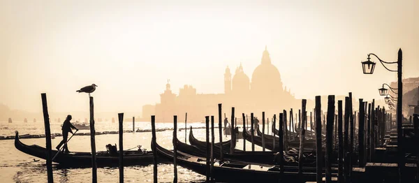 Romántica ciudad italiana de Venecia, Patrimonio de la Humanidad: barcos de madera venecianos tradicionales, gondolero e iglesia católica Basílica de Santa Maria della Salute en el fondo brumoso — Foto de Stock