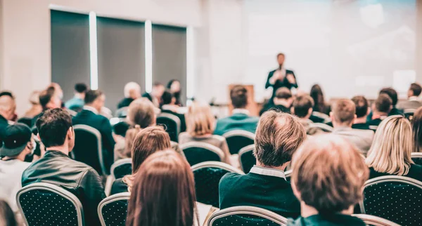 Talmannen håller ett föredrag i konferenssalen på affärsevenemanget. Bakifrån av oigenkännliga människor i publiken i konferenslokalen. Affärs- och entreprenörskapskoncept. — Stockfoto