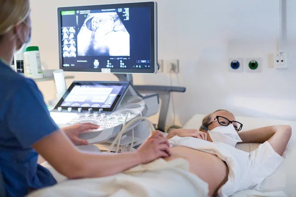 Närbild av en gravid kvinna som har ultraljudsundersökning på kliniken. Koncept för hälso- och sjukvård — Stockfoto